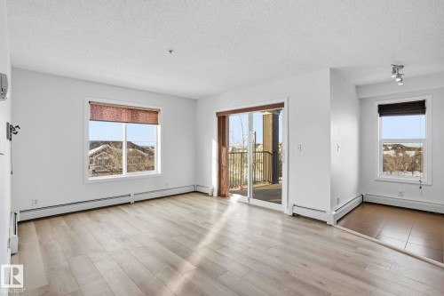 Unfurnished room with a textured ceiling, light wood-style flooring, and a baseboard heating unit - 318 530 Watt Boulevard, Edmonton, AB - Indoor