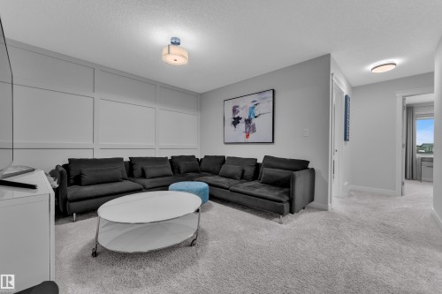 Living area with light colored carpet, a textured ceiling, and a decorative wall - 906 Berg Place, Leduc, AB - Indoor Photo Showing Living Room
