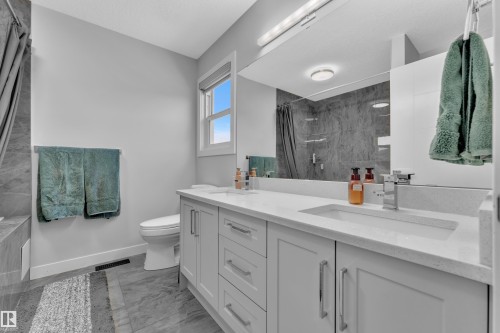 Full bathroom featuring double vanity, tiled shower, and light marble finish flooring - 906 Berg Place, Leduc, AB - Indoor Photo Showing Bathroom