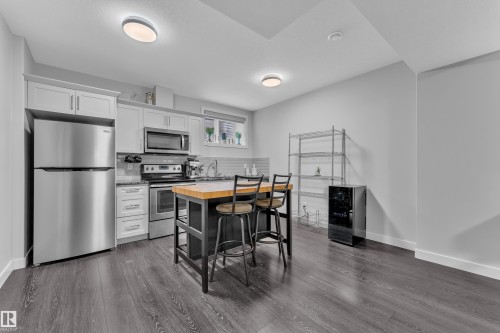 Kitchen featuring stainless steel appliances, butcher block countertops, decorative backsplash, white cabinetry, and dark wood-type flooring - 906 Berg Place, Leduc, AB - Indoor Photo Showing Kitchen