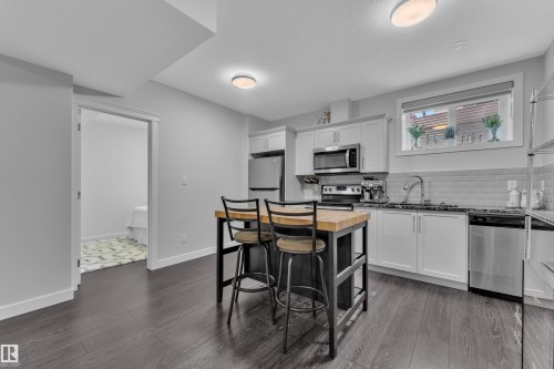 Kitchen with stainless steel appliances, white cabinetry, wood counters, dark wood-type flooring, and tasteful backsplash - 906 Berg Place, Leduc, AB - Indoor Photo Showing Kitchen With Upgraded Kitchen