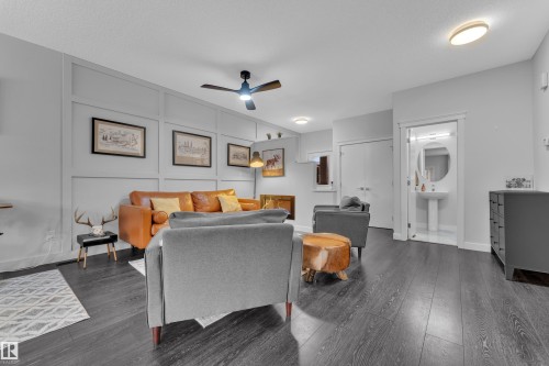 Living room featuring a ceiling fan, a decorative wall, and dark wood-style floors - 906 Berg Place, Leduc, AB - Indoor