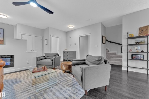 Living room with a ceiling fan, a glass covered fireplace, and wood finished floors - 906 Berg Place, Leduc, AB - Indoor Photo Showing Living Room