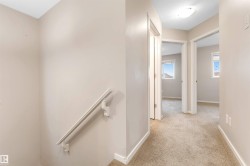 Hallway with light colored carpet and an upstairs landing - 