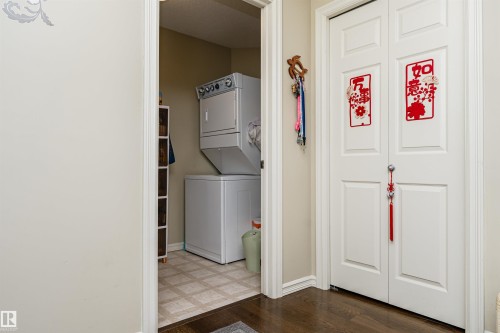 Laundry room featuring stacked washing machine and dryer and dark wood-type flooring - 314 4403 23 Street, Edmonton, AB - Indoor Photo Showing Laundry Room