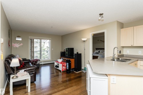 Kitchen featuring a peninsula, open floor plan, dark wood-type flooring, light countertops, and baseboard heating - 314 4403 23 Street, Edmonton, AB - Indoor