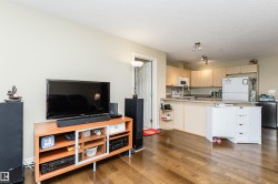 Kitchen with dark wood-type flooring, light countertops, white appliances, a textured ceiling, and light wood finish cabinetry - 