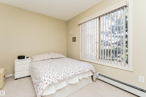 Carpeted bedroom with baseboard heating and a textured ceiling - 314 4403 23 Street, Edmonton, AB - Indoor Photo Showing Bedroom