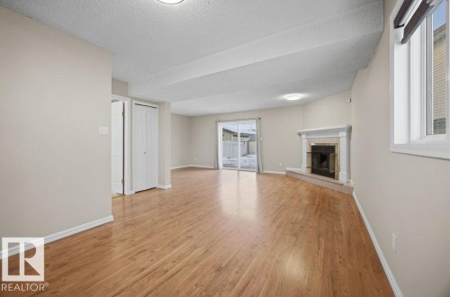 Unfurnished living room with a textured ceiling, light wood-style floors, a tile fireplace, and healthy amount of natural light - 736 Johns Road, Edmonton, AB - Indoor With Fireplace