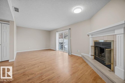 Unfurnished living room with a textured ceiling, light wood finished floors, and a tile fireplace - 736 Johns Road, Edmonton, AB - Indoor Photo Showing Other Room With Fireplace