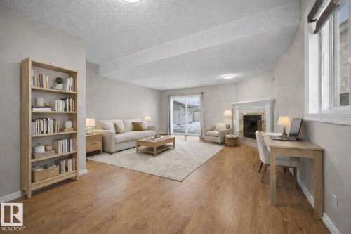Living area with a tiled fireplace, wood finished floors, and a textured ceiling - 736 Johns Road, Edmonton, AB - Indoor Photo Showing Other Room With Fireplace