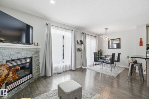 Living area with plenty of natural light, a stone fireplace, wood finished floors, suspended lighting, and a textured ceiling - 64 2004 Grantham Court, Edmonton, AB - Indoor Photo Showing Living Room With Fireplace