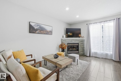 Living area featuring a stone fireplace, wood finished floors, and recessed lighting - 64 2004 Grantham Court, Edmonton, AB - Indoor Photo Showing Living Room With Fireplace