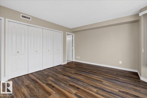 Unfurnished bedroom with a textured ceiling, a closet, and dark wood-type flooring - 402 10649 Saskatchewan Drive, Edmonton, AB - Indoor Photo Showing Other Room