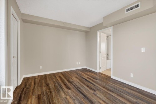 Unfurnished bedroom featuring dark wood finished floors and baseboards - 402 10649 Saskatchewan Drive, Edmonton, AB - Indoor Photo Showing Other Room