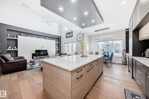 Kitchen featuring light wood finished floors, open floor plan, built in features, decorative light fixtures, and two tone cabinets - 17112 68 Street, Edmonton, AB - Indoor Photo Showing Kitchen