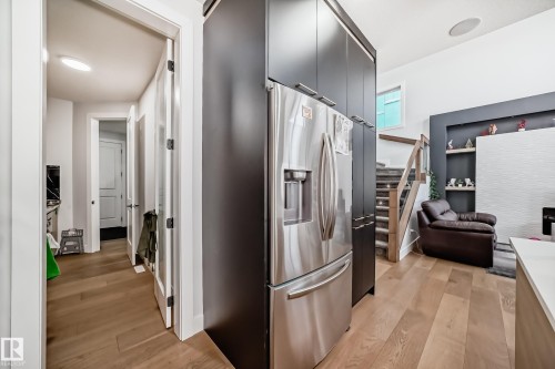 Kitchen with light wood-style flooring, modern cabinets, stainless steel fridge, and open floor plan - 17112 68 Street, Edmonton, AB - Indoor Photo Showing Other Room