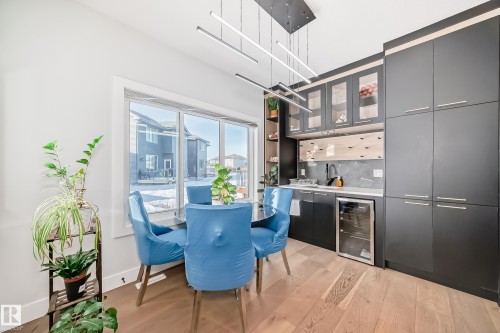 Indoor bar featuring open shelves, modern cabinets, beverage cooler, light wood finished floors, and decorative backsplash - 17112 68 Street, Edmonton, AB - Indoor