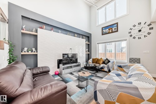 Living room featuring plenty of natural light, built in features, wood finished floors, and a high ceiling - 17112 68 Street, Edmonton, AB - Indoor Photo Showing Living Room