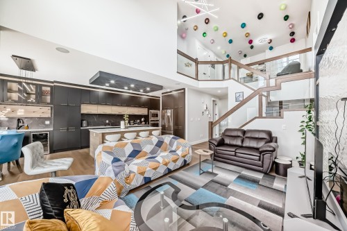 Living room with light wood finished floors, beverage cooler, a high ceiling, and recessed lighting - 17112 68 Street, Edmonton, AB - Indoor