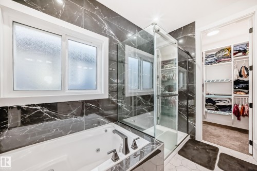 Full bathroom featuring a whirlpool tub, a marble finish shower, a walk in closet, and tile walls - 17112 68 Street, Edmonton, AB - Indoor Photo Showing Bathroom