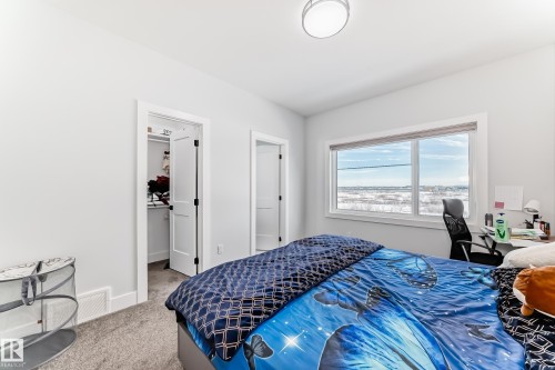 Bedroom with a walk in closet, light carpet, and a desk - 17112 68 Street, Edmonton, AB - Indoor Photo Showing Bedroom