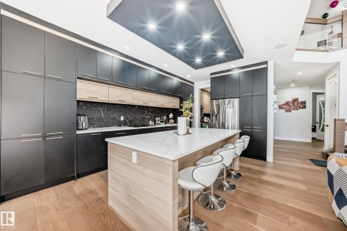 Kitchen featuring two tone color scheme, a kitchen bar, light wood finished floors, modern cabinets, and a center island - 17112 68 Street, Edmonton, AB - Indoor Photo Showing Kitchen