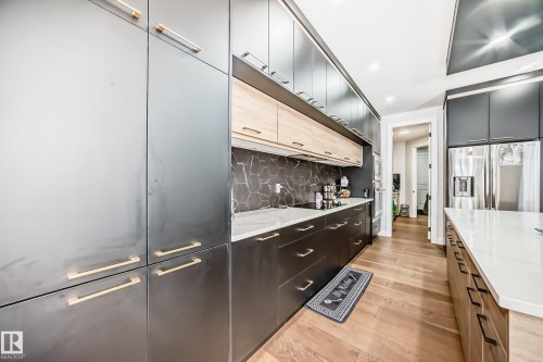 Dual tone kitchen featuring dual tone cabinets, light wood-style floors, stainless steel fridge, modern cabinets, and light stone counters - 17112 68 Street, Edmonton, AB - Indoor Photo Showing Other Room