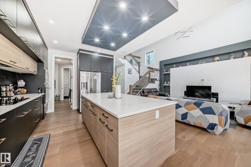 Kitchen with dual tone cabinets, open floor plan, light wood finished floors, modern cabinets, and light stone counters - 17112 68 Street, Edmonton, AB - Indoor Photo Showing Kitchen