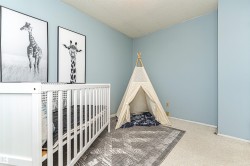 Carpeted bedroom featuring a textured ceiling and a nursery area - 