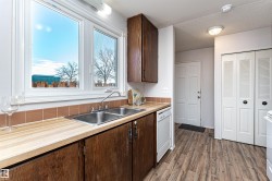 Kitchen featuring dark brown cabinets, light countertops, dark wood-type flooring, and a textured ceiling - 