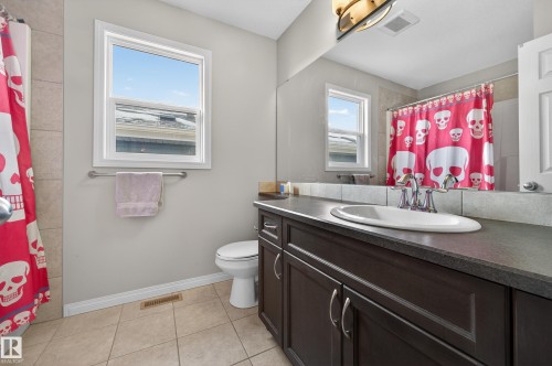 Bathroom with a shower with curtain, vanity, and light tile patterned flooring - 5256 21 Avenue, Edmonton, AB - Indoor Photo Showing Bathroom