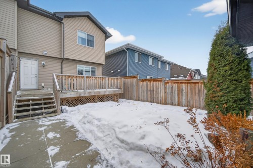 Snow covered rear of property featuring a fenced backyard, a wooden deck, and a residential view - 5256 21 Avenue, Edmonton, AB - Outdoor With Deck Patio Veranda