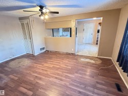 Empty room with dark wood-type flooring, a textured ceiling, and a ceiling fan. - 