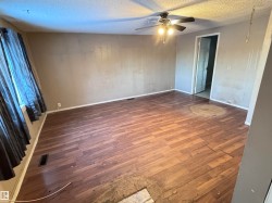 Unfurnished bedroom with dark wood-type flooring, a textured ceiling, and a ceiling fan - 