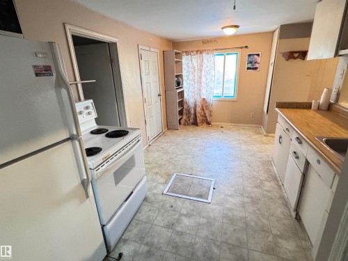 Kitchen featuring white appliances, light flooring, white cabinetry, and light countertops - 10407 102 Street, Westlock, AB - Indoor Photo Showing Kitchen