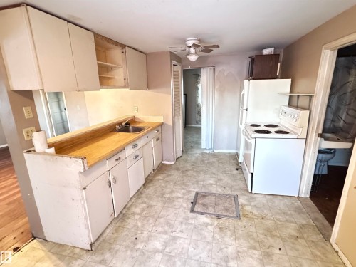 Kitchen with white appliances, a ceiling fan, open shelves, and cream cabinets - 10407 102 Street, Westlock, AB - Indoor Photo Showing Kitchen