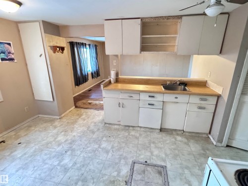 Kitchen with white cabinetry, light countertops, light flooring, open shelves, and white stove - 10407 102 Street, Westlock, AB - Indoor Photo Showing Kitchen