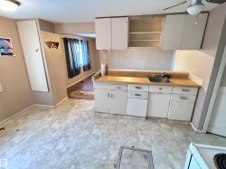 Kitchen with white cabinetry, light countertops, light flooring, open shelves, and white stove - 