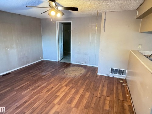Unfurnished dining area featuring dark wood-style floors, a textured ceiling, wooden walls, and a ceiling fan - 10407 102 Street, Westlock, AB - Indoor Photo Showing Other Room