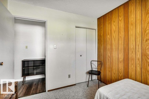 Carpeted bedroom with a closet, a textured ceiling, and wood walls - 8919 152A Avenue, Edmonton, AB - Indoor Photo Showing Bedroom