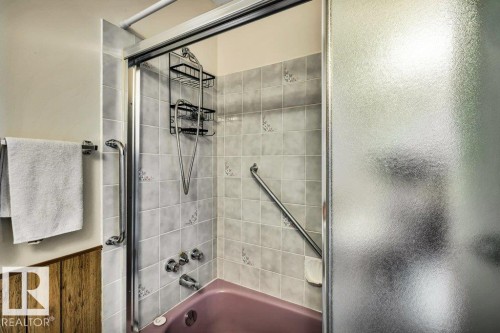 Bathroom with enclosed tub / shower combo, wainscoting, and wooden walls - 8919 152A Avenue, Edmonton, AB - Indoor Photo Showing Bathroom