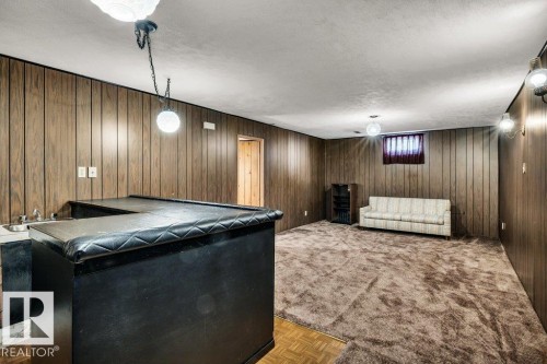 Living room featuring a textured ceiling, wooden walls, and parquet floors - 8919 152A Avenue, Edmonton, AB - Indoor Photo Showing Other Room