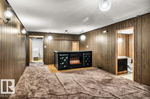 Bar area featuring light carpet, wooden walls, and a textured ceiling - 8919 152A Avenue, Edmonton, AB - Indoor
