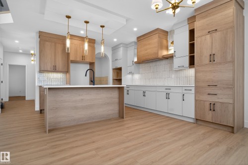 Two tone kitchen with decorative backsplash, modern cabinets, light wood-style floors, hanging lights, and a kitchen island with sink - 26 Rosa Crescent, St. Albert, AB - Indoor Photo Showing Kitchen With Upgraded Kitchen
