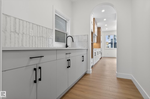 Kitchen with white cabinetry, light wood-type flooring, arched walkways, recessed lighting, and modern cabinets - 26 Rosa Crescent, St. Albert, AB - Indoor Photo Showing Other Room
