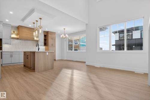 Kitchen with an island with sink, suspended lighting, light wood-style flooring, open shelves, and modern cabinets - 26 Rosa Crescent, St. Albert, AB - Indoor Photo Showing Kitchen