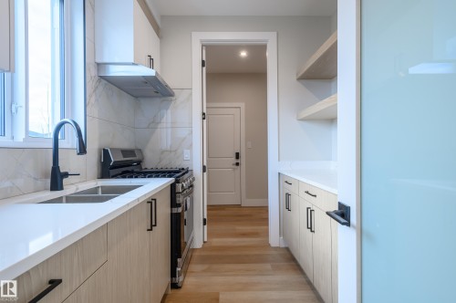 Kitchen with gas stove, decorative backsplash, white cabinetry, light stone countertops, and light wood-style flooring - 16 Middleton Close, Leduc, AB - Indoor Photo Showing Kitchen With Double Sink