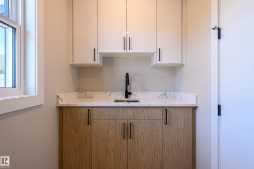 Bar with white cabinetry, healthy amount of natural light, and light stone counters - 16 Middleton Close, Leduc, AB - Indoor Photo Showing Kitchen