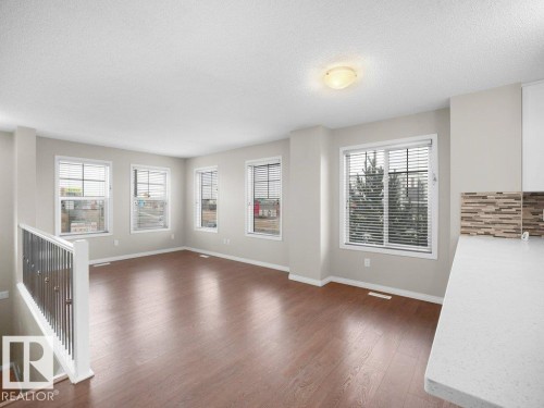 Unfurnished living room with dark wood-style floors and a textured ceiling - 15 7385 Edgemont Way, Edmonton, AB - Indoor